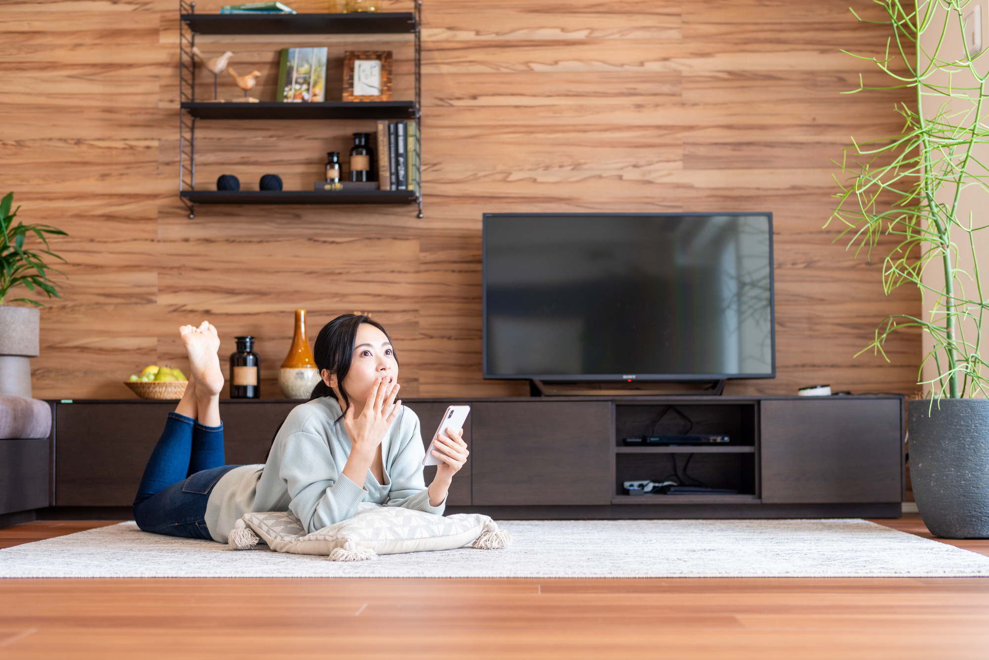 Japanese woman in the living room, wondering what show to watch next.