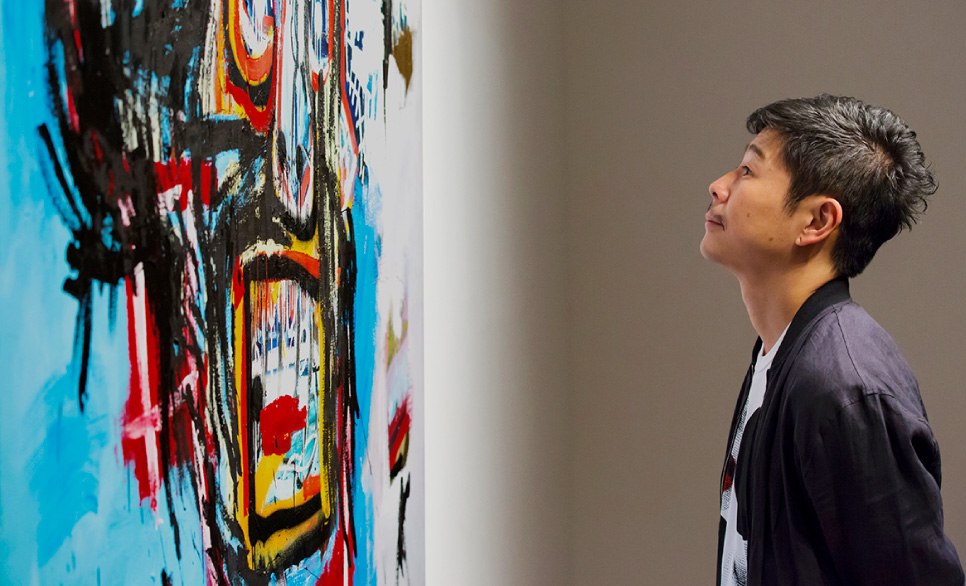 Yusaku Maezawa examining original by Jean-Michel Basquiat