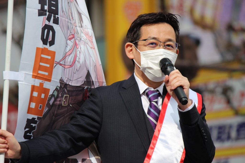 Ken Akamatsu holding a banner that says "Protect freedom of expression".
